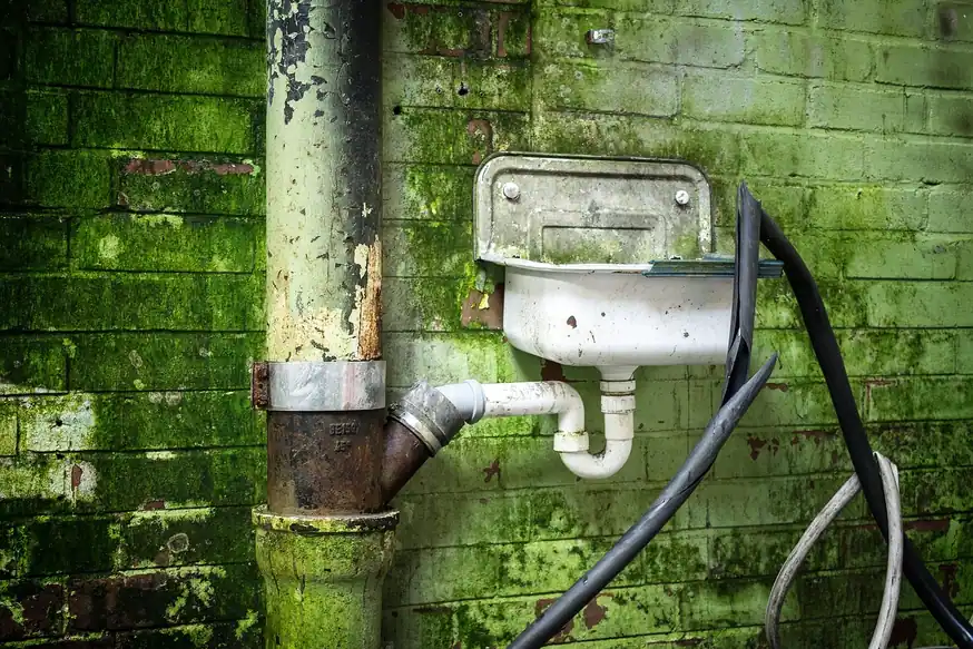 Lavabo antiguo con su sifón de plástico conectado a la bajante de hierro de la pared
