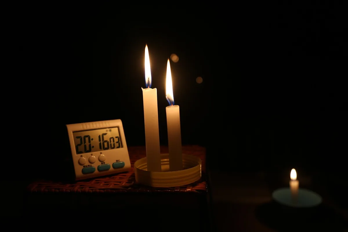 Velas encendidas junto a un reloj en una casa a oscuras, como cuando salta el diferencial al enchufar un aparato