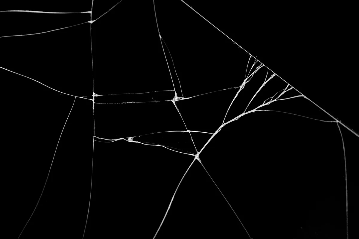 Grietas en un cristal negro, como las de una vitrocerámica rajada que hay que dejar de usar hasta la revisión