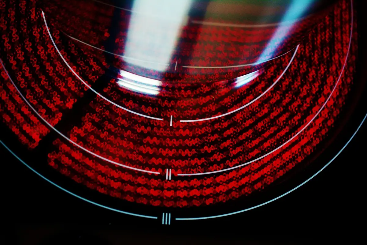 Resistencia radiante encendida al rojo bajo el cristal de una vitrocerámica, con tres aros serigrafiados I, II y III