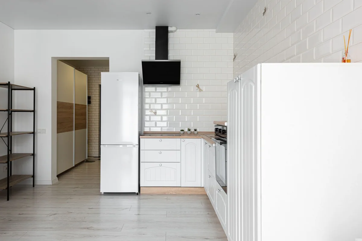 Frigorífico combi blanco de libre instalación en una cocina con azulejos blancos