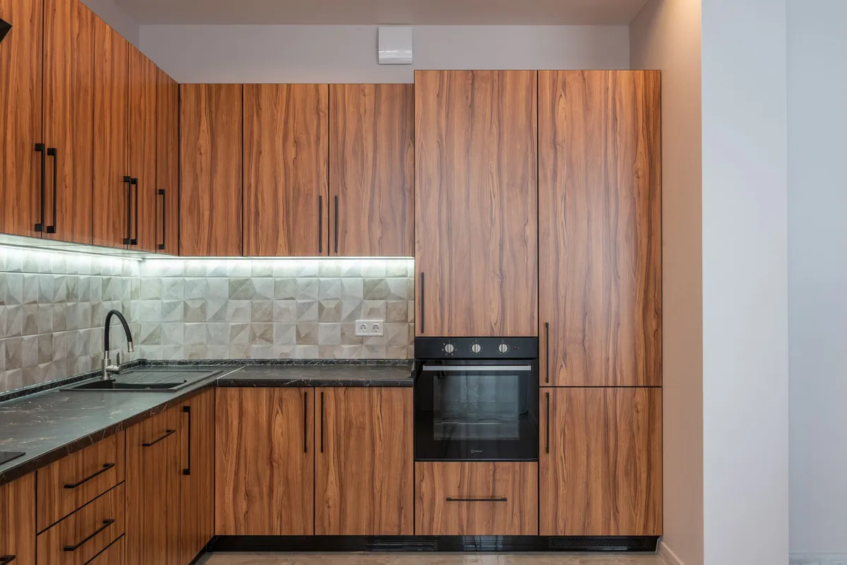 Horno empotrado en un mueble columna con la puerta cerrada, en una cocina de madera