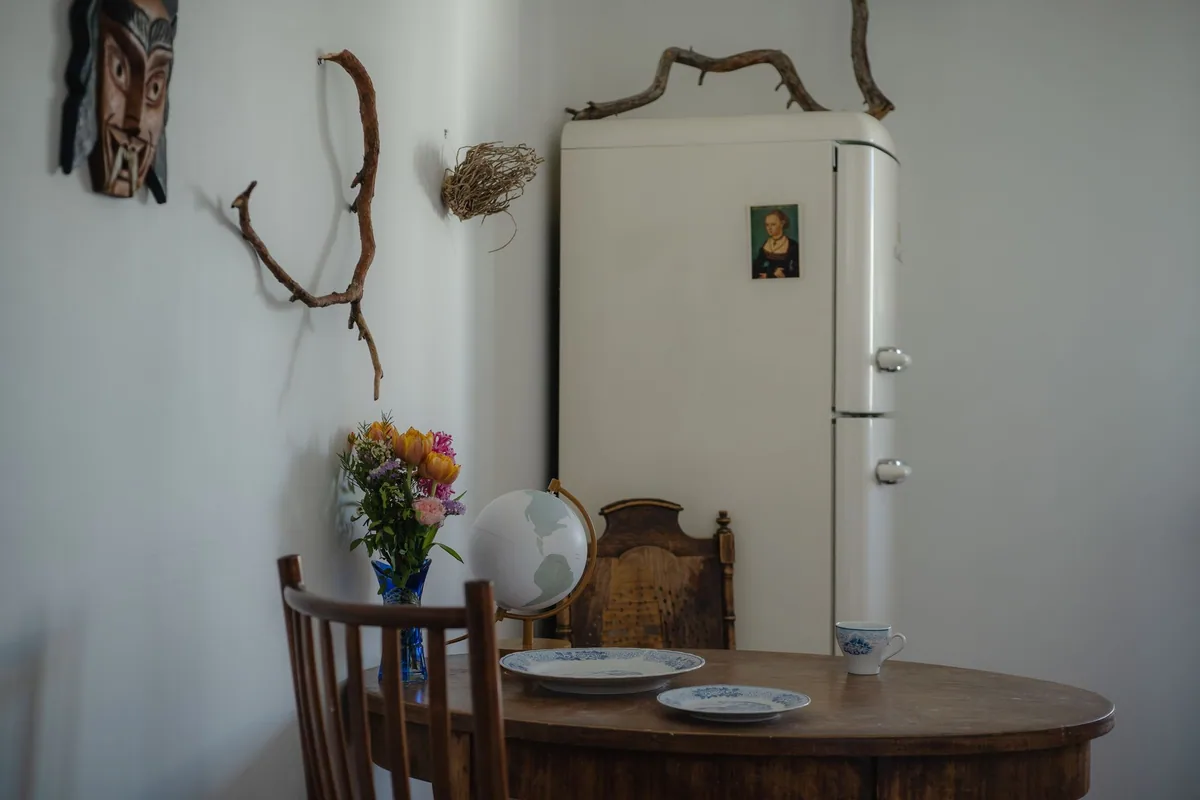 Frigorífico de estilo retro color crema, con esquinas redondeadas y tiradores cromados, junto a una mesa de madera