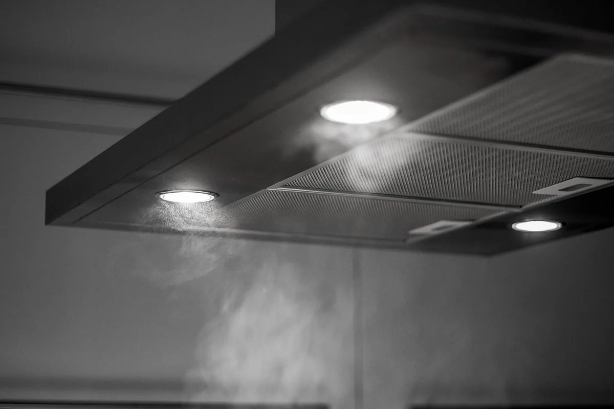 Parte inferior de una campana extractora, con los filtros metálicos y las luces encendidas mientras aspira el vapor