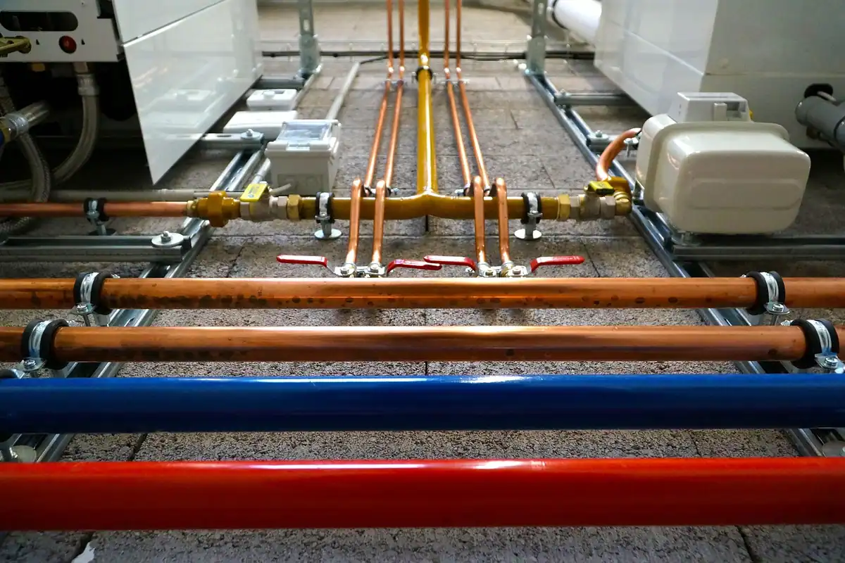 Tomas de gas y de agua con sus llaves de paso bajo unos aparatos de calefacción de pared