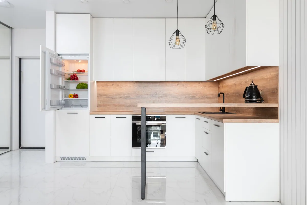 Frigorífico integrado con la puerta abierta y las baldas a la vista en una cocina blanca