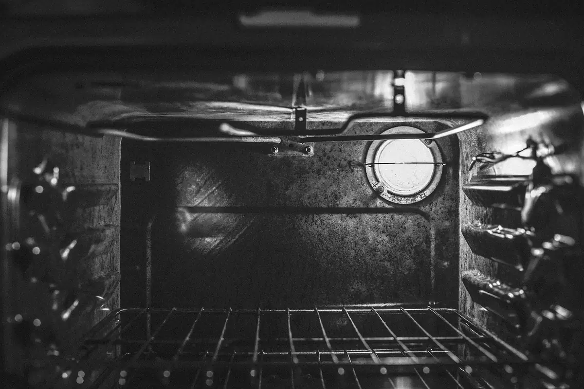 Interior de un horno con la bombilla encendida, las paredes y la rejilla a la vista