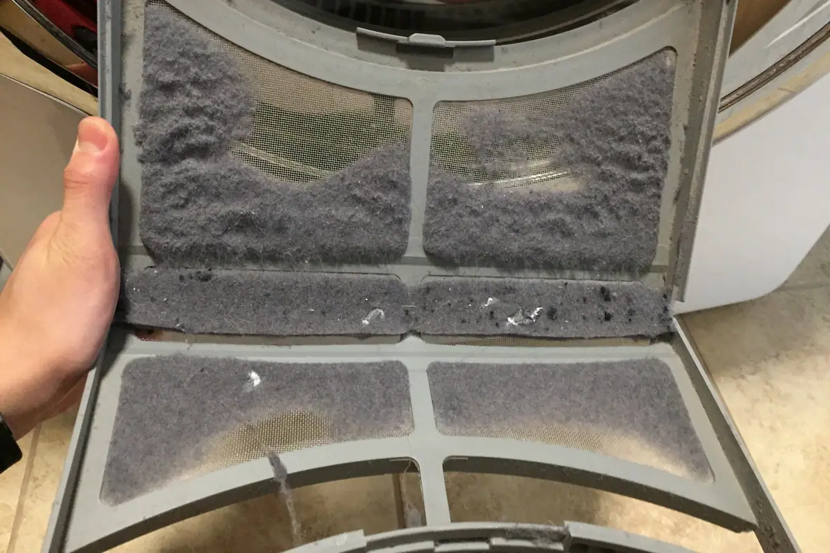 Filtro de pelusa de una secadora abierto y lleno de pelusa